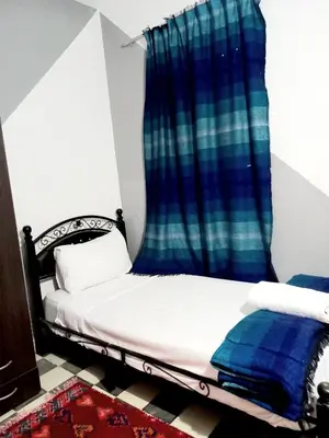 a bedroom with a bed with a blue curtain at Hadi house in Fès