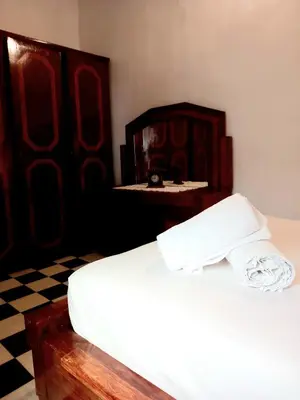 a bedroom with a white bed and a wooden dresser at Hadi house in Fès