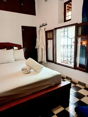 a bedroom with a bed and a window with a robe at Hadi house in Fès