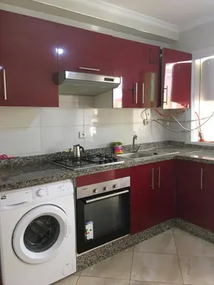 a kitchen with red cabinets and a washing machine at appartement tanger in Oulad Akkou