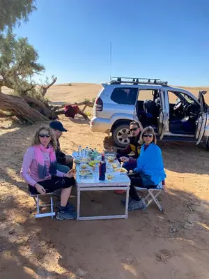 a group of people sitting around a table in the desert at Desert Mhamid in Mhamid