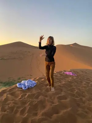 a woman standing in the sand in the desert at Desert Mhamid in Mhamid