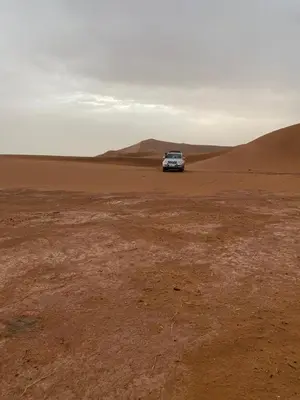 a car parked in the middle of the desert at Desert Mhamid in Mhamid