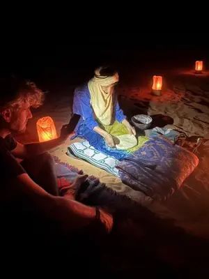 a woman sitting on a blanket next to a man at Desert Mhamid in Mhamid