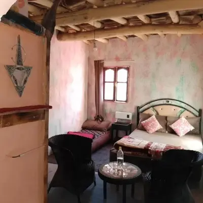 a bedroom with a bed and a table and chairs at امردول تسكوكت امرزكان ورزازات in Ouarzazate