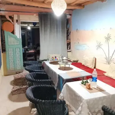 a room with tables and chairs and a wall with a mural at امردول تسكوكت امرزكان ورزازات in Ouarzazate