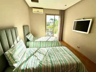 a bedroom with two beds and a tv on the wall at Luxueux appartement à Prestigia avec Wifi Fibre 100Mo in Fès