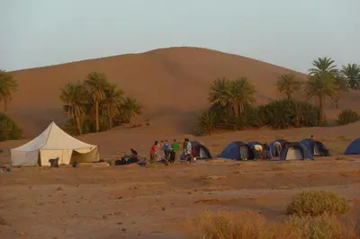 a group of people standing in a desert with tents at Casa de las Estrellas in Mhamid