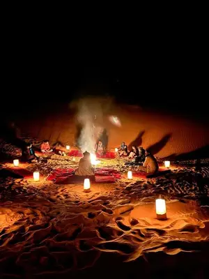 a group of people sitting on a beach with candles at Casa de las Estrellas in Mhamid