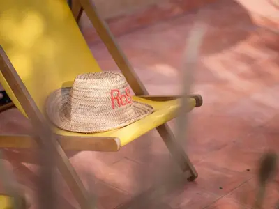 a straw hat sitting on a yellow chair at Villa Roswell with Pool Privatisation in Heddad