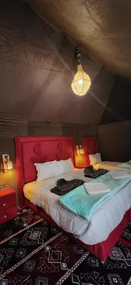 a bedroom with a large bed with a red headboard at مرزوكة in Merzouga