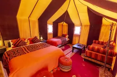 a bedroom with two beds and a chair in a room at مرزوكة in Merzouga