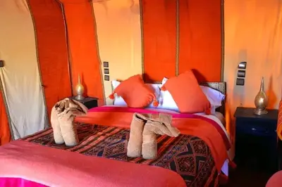 a bedroom with a red bed with towels on it at مرزوكة in Merzouga