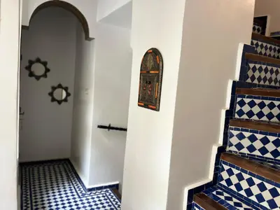 a hallway with blue and white tiled floors and stairs at Riad Dar Mama Laila in Fès