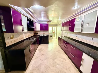 a large kitchen with purple cabinets and marble floors at Fabuleux appartement au Centre Ville avec Wifi 100 Mo in Fès