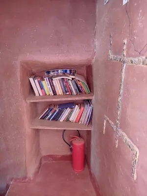 a room with a shelf with books and a red cup at Casa Rural Todra Gorges in Tinerhir