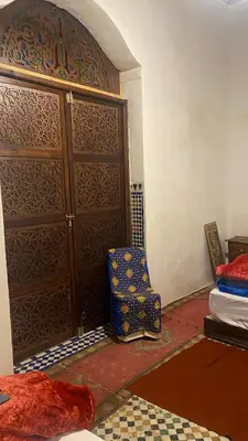 a room with a large wooden door and a chair at dar ben issa in Fès