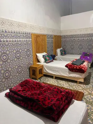 a bedroom with two beds and a red blanket at dar ben issa in Fès