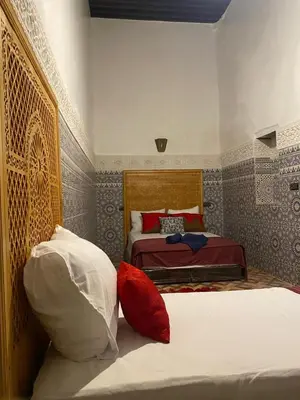 a bedroom with two beds with red and white pillows at dar ben issa in Fès