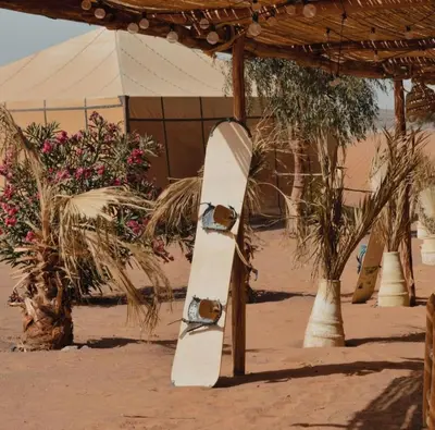 a snowboard sitting in the sand under a tent at Melody Desert Camp Merzouga in Merzouga
