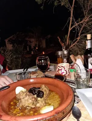 a plate of food on a table with a glass of wine at Melody Desert Camp Merzouga in Merzouga