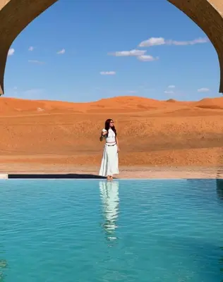 a woman standing in front of a body of water at Melody Desert Camp Merzouga in Merzouga
