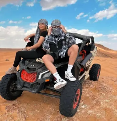 two people sitting in the back of a wheeler in the desert at Melody Desert Camp Merzouga in Merzouga