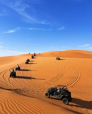 a group of people driving in the desert at Melody Desert Camp Merzouga in Merzouga