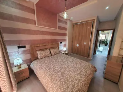 a bedroom with a bed and a striped wall at Meknes centre ville Appartement neuf moderne et bien équipé in Meknès