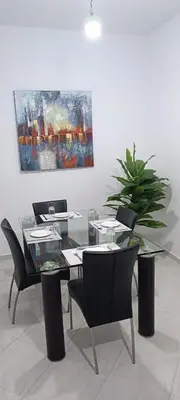 a dining room with a table and chairs and a painting at Appartement azrou in Azrou