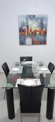 a glass table with chairs and a painting on the wall at Appartement azrou in Azrou