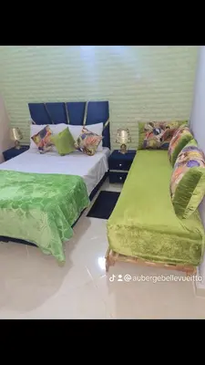 a bedroom with two beds with green sheets and pillows at Hôtel mandar itto in Azrou