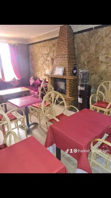 a restaurant with tables and chairs and a brick fireplace at Hôtel mandar itto in Azrou