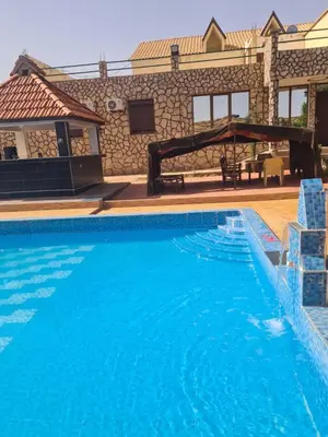 a large blue swimming pool in front of a building at Hôtel mandar itto in Azrou