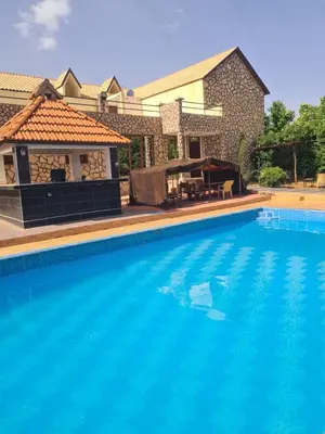 a large swimming pool with a gazebo next to a house at Hôtel mandar itto in Azrou