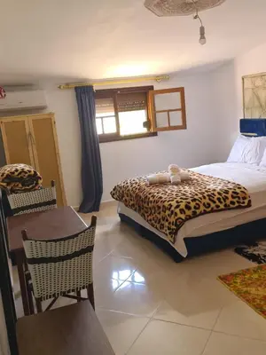 a bedroom with a leopard print bed and a table at Hôtel mandar itto in Azrou