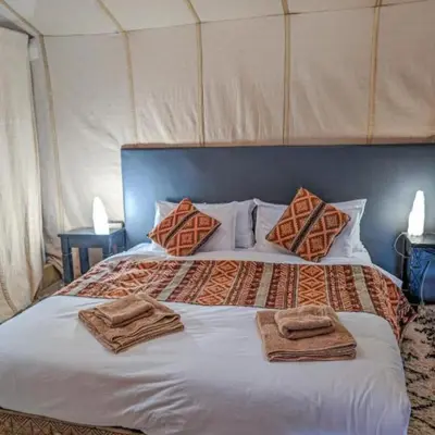 a bed in a tent with towels on it at Unique Sahara Camp in Merzouga