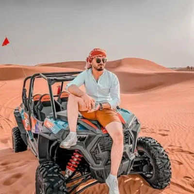 a man sitting on a wheeler in the desert at Unique Sahara Camp in Merzouga