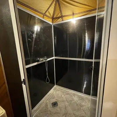 a bathroom with a shower with a glass door at Unique Sahara Camp in Merzouga