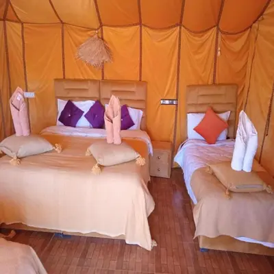 a bedroom with two beds in a tent at Unique Sahara Camp in Merzouga