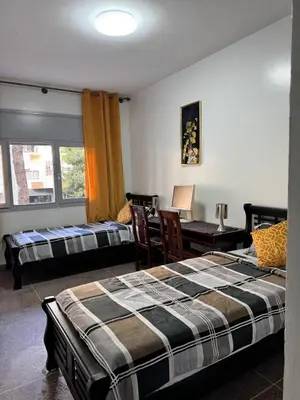 a bedroom with two beds and a desk and a table at Appartement Rabat Agdal in Oulad Akkou