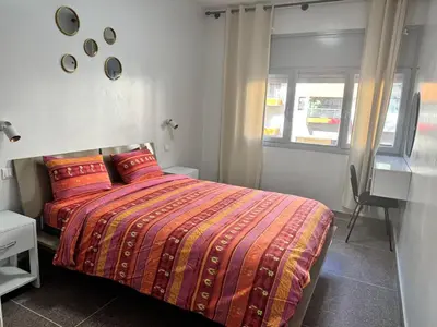 a bedroom with a bed with a colorful comforter and a window at Appartement Rabat Agdal in Oulad Akkou