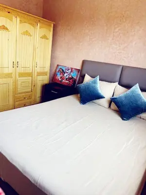 a bedroom with a large white bed with blue pillows at Bel appartement 2 chambres au cœur de Marrakech in Oulad Akkou