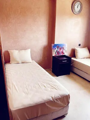a bedroom with a bed and a table with a picture at Bel appartement 2 chambres au cœur de Marrakech in Oulad Akkou