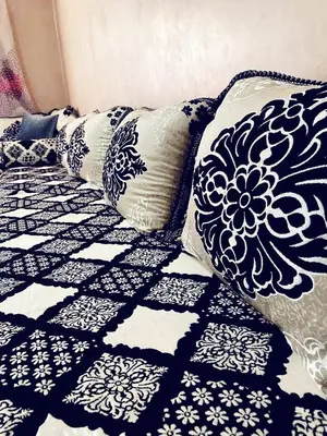 a bed with black and white pillows on it at Bel appartement 2 chambres au cœur de Marrakech in Oulad Akkou