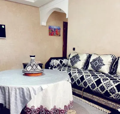 a room with a bed and a table with a vase on it at Bel appartement 2 chambres au cœur de Marrakech in Oulad Akkou
