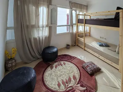 a room with two bunk beds and a rug at Tayyurt Blue waves Beach house's in Oulad Akkou