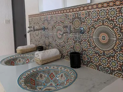 a bathroom with two sinks and a mosaic wall at Tayyurt Blue waves Beach house's in Oulad Akkou