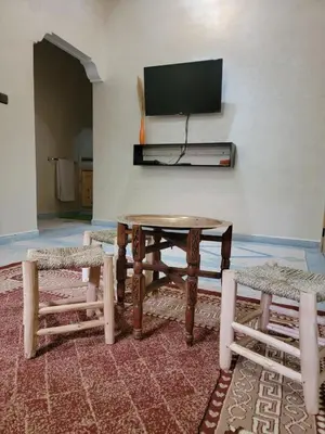 a room with a table and two chairs and a tv at Blue Palm apartment in Ouarzazate