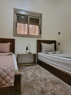 a bedroom with two beds and a window at Blue Palm apartment in Ouarzazate